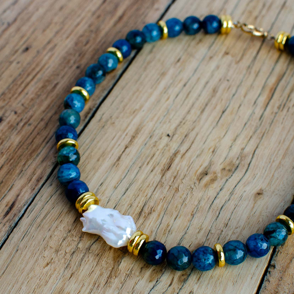 Necklace with blue beads and a white crystal on a wooden surface