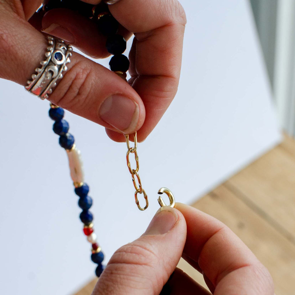Close-up of hands working with jewelry on a wooden surface