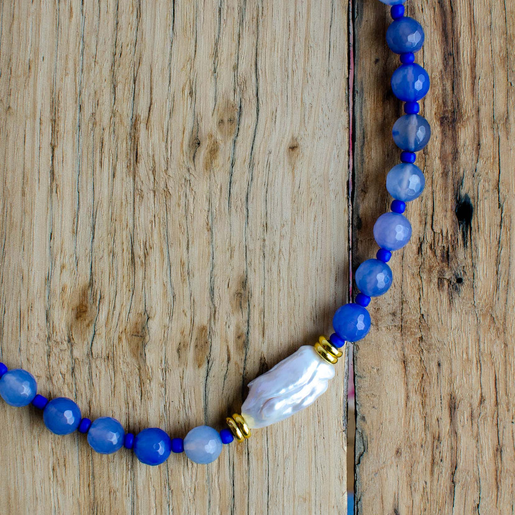 Beaded necklace with a large pearl feature bead on a wooden surface