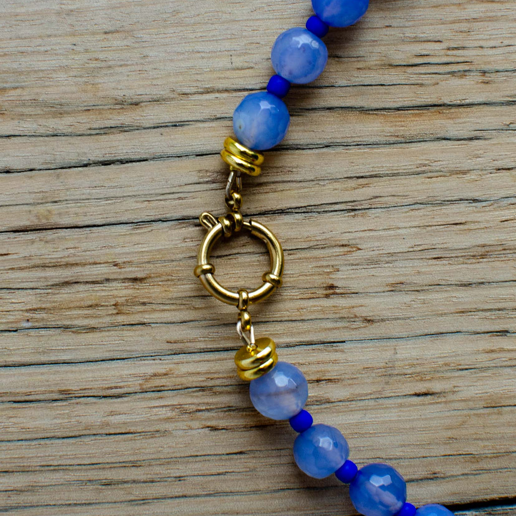 Blue beaded bracelet with a gold clasp on a wooden surface
