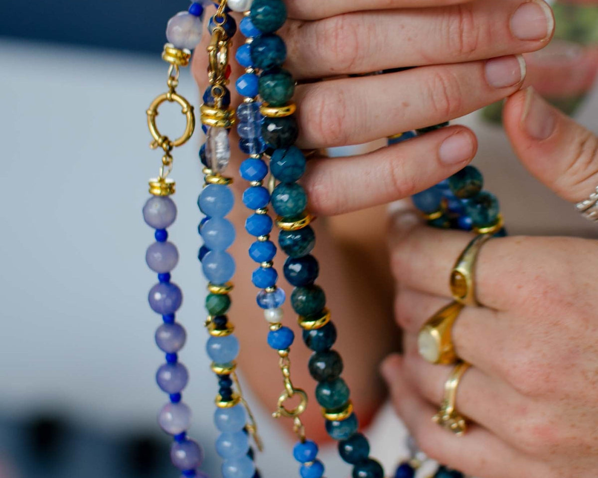 Close-up of hands holding colorful beaded necklaces with a blurred background